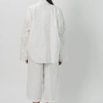 Back view of snow buck ls shirt on model wearing white shirt and pants, against a white background.