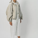 Side view of desert colima zip up hoodie on model wearing white shirt and pants, against a white background.