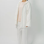 Front slanted view of off white condor rev jacket on model wearing white pants and pink top, against a white background.