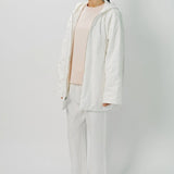 Front slanted view of off white condor rev jacket on model wearing white pants and pink top, against a white background.