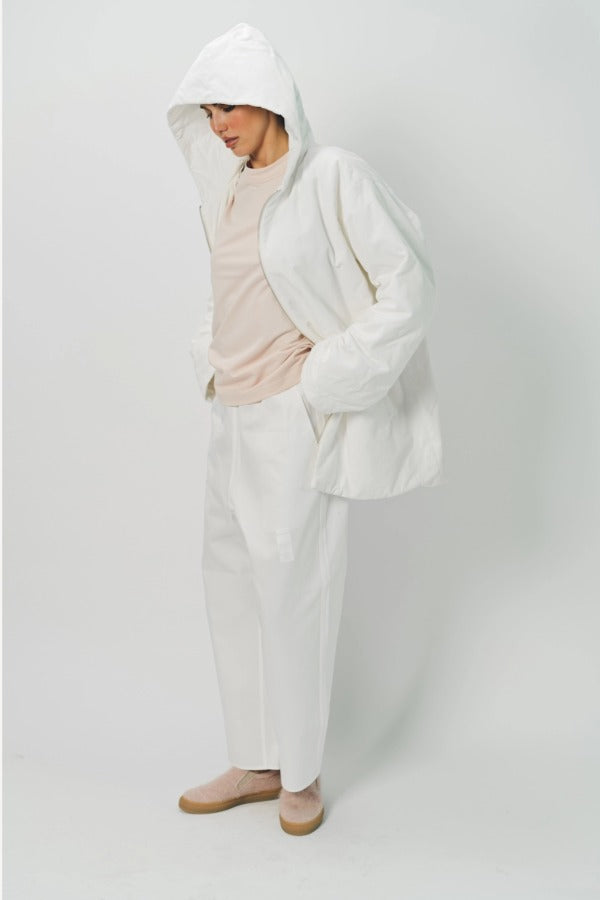 Hooded view of off white condor rev jacket on model wearing white pants and pink shirt, against a white background.