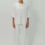 Front view of off white thebe ss cropped sweatshirt on model wearing white pants, against a white background.