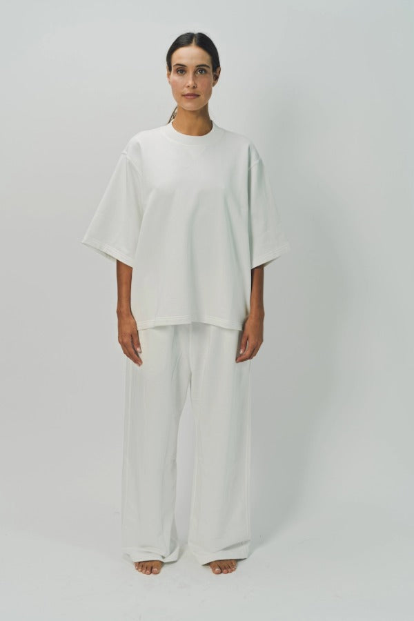 Front view of off white thebe ss cropped sweatshirt on model wearing white pants, against a white background.