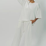 Alternate front view of off white thebe ss cropped sweatshirt on model wearing white pants, against a white background.