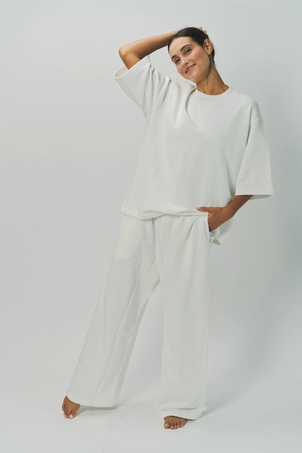 Alternate front view of off white thebe ss cropped sweatshirt on model wearing white pants, against a white background.