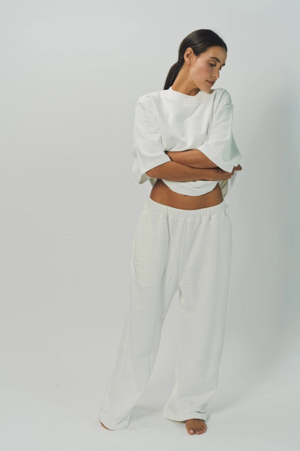 Alternate front view of off white thebe ss cropped sweatshirt on model wearing white pants, against a white background.