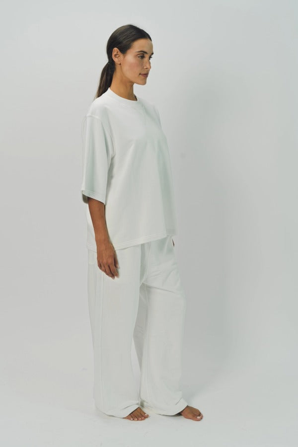 Side view of off white tower sweatpants on model wearing white sweatshirt, against a white background.