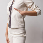 Side closeup view of the pockets of white my way jacket on model wearing white leather pants, against a white background.