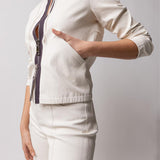 Side closeup view of the pockets of white my way jacket on model wearing white leather pants, against a white background.