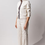 Alternate side view of white my way jacket on model wearing white leather pants, against a white background.