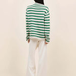 Back view of fern/white costeau stripe cardigan on model wearing white pants and heels, against a white background.