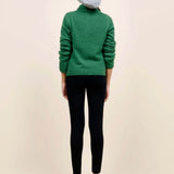 Back view of fern laurel polo on model wearing black leggings, white heels and a beanie against a white background.