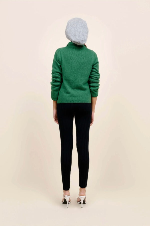 Back view of fern laurel polo on model wearing black leggings, white heels and a beanie against a white background.