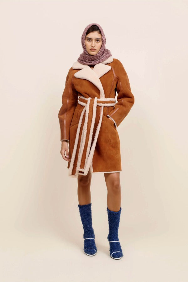 Front view of bordeaux marl triangle body scarf on model wearing orange coat, blue socks and white heels, against a white background.