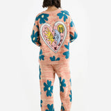 Back view of multi floral the elder statesman sun and moon cardigan on model wearing matching pants and heels, against white background.