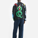 Back view of multi mythical creatures on model wearing blue trousers and black sandals, against white background.