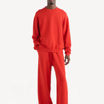 Front view of sanguinello daily crew top on dark-haired model wearing red trousers, against a white background.