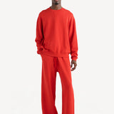 Front view of sanguinello daily crew top on dark-haired model wearing red trousers, against a white background.
