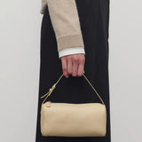 Front view of sand 90's bag on model wearing a beige sweater and black pants, against a white background.