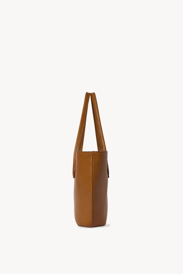 Side view of cuir alger tote on white background, with no model shown.