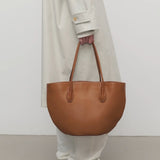 Front view of cuir alger tote on model wearing snow trench coat and loafers, against a white background.