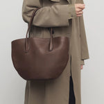 Front view of deep brown alger tote on model wearing beige trench coat, against a white background.