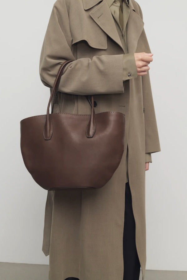 Front view of deep brown alger tote on model wearing beige trench coat, against a white background.