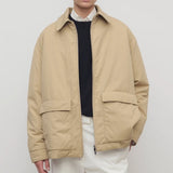 Front view of sand aurelius jacket on model wearing black sweater, white shirt and pants, against a white background.