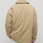 Back view of sand aurelius jacket on model wearing white pants, against a white background.
