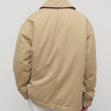 Back view of sand aurelius jacket on model wearing white pants, against a white background.