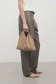 Front view of beige melange suede bag on white background, with model wearing khaki trousers and a white shirt with sandals.