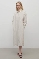 A blonde model standing at a front view in the midi dress with white background.