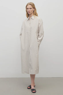 A blonde model standing at a front view in the midi dress with white background.