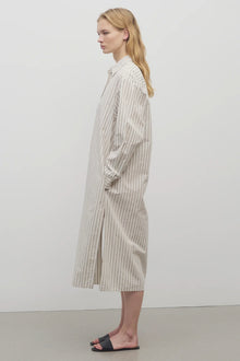 A blonde model standing at a side view in the midi dress with white background.