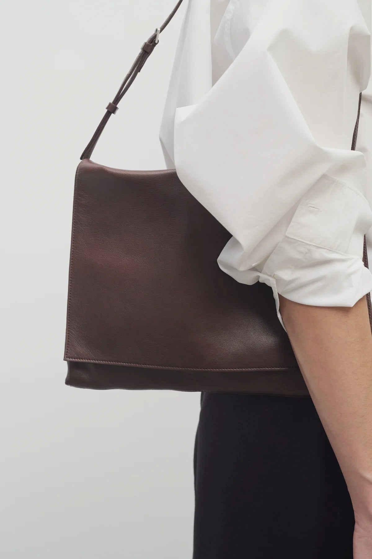 Front view of brown melange nan shoulder bag on model wearing white collar shirt with black trousers, against a white background.