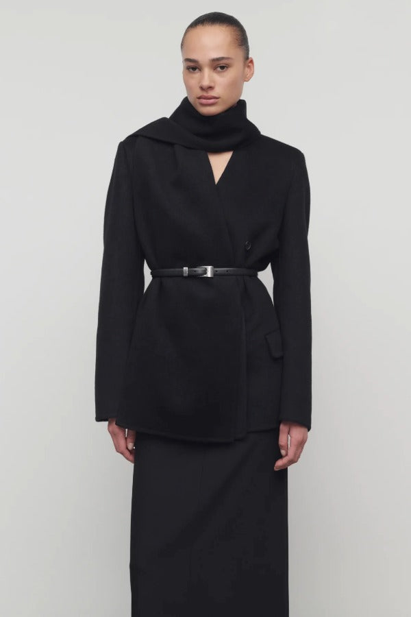 Front view of black calitra jacket on model in black skirt, against a white background.