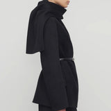 Side view of black calitra jacket on model wearing black skirt, against a white background