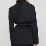 Back view of black calitra jacket on model wearing black skirt, against a white background.