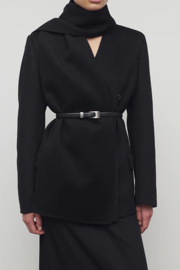Front closeup view of black calitra jacket on model wearing black skirt, against a white background.
