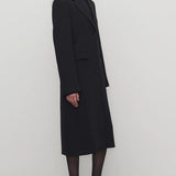 Side view of black cerys coat on model wearing black heels, against a white background.