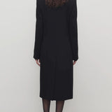 Back view of black cerys coat on model wearing black heels, against a white background.