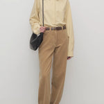 Front view of anise clair pant on model wearing yellow shirt and mules, against a white background.