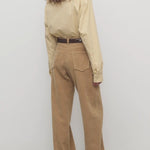 Back view of anise clair pant on model wearing yellow shirt and mules, against a white background.
