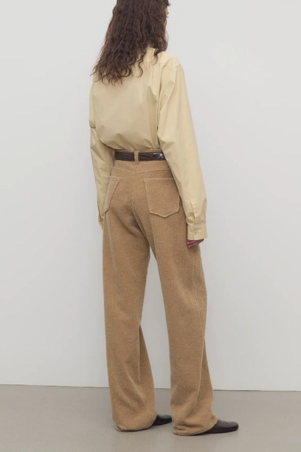 Back view of anise clair pant on model wearing yellow shirt and mules, against a white background.