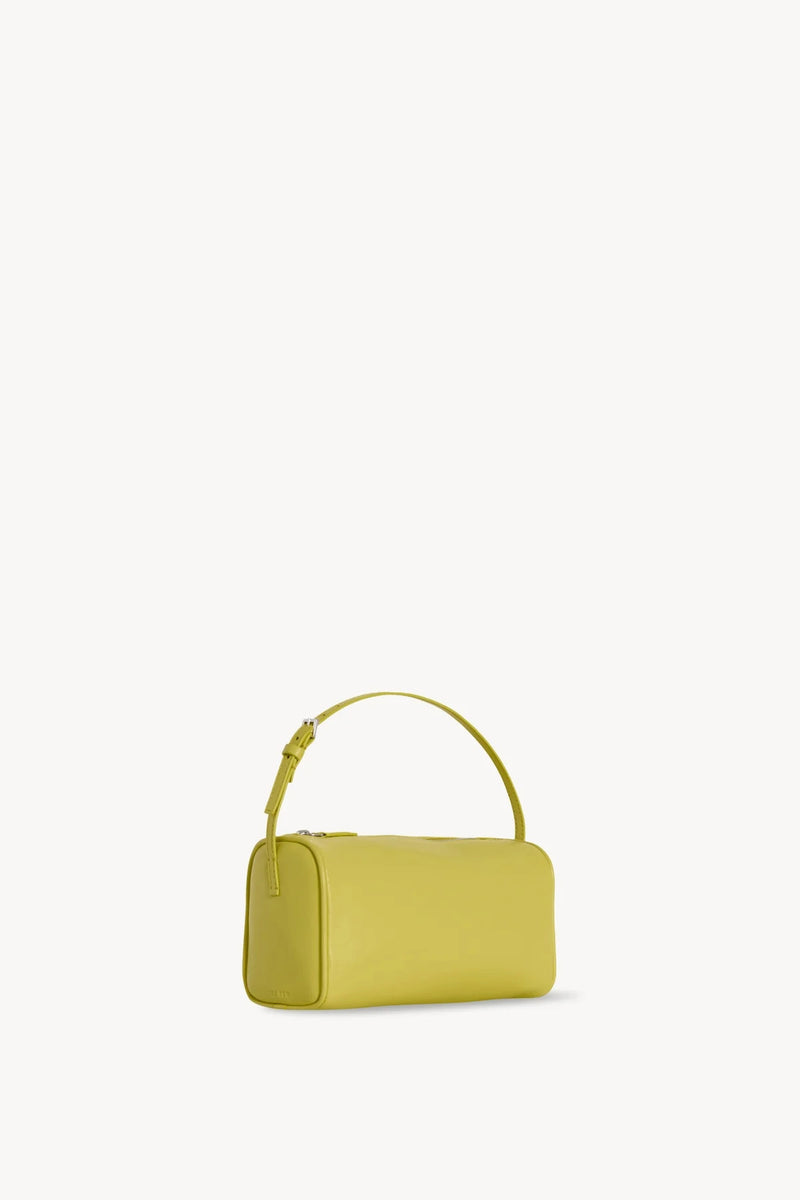 Side slanted view of coppery yellow leather bag on white background, with no model shown.