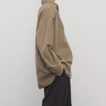 Side view of beige corduroy sisilia shirt on model wearing grey pants, against a white background
