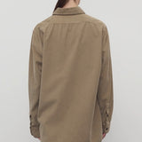 Back view of beige corduroy sisilia shirt on model wearing grey pants, against a white background.