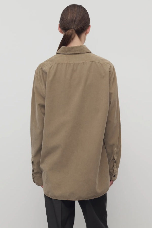 Back view of beige corduroy sisilia shirt on model wearing grey pants, against a white background.
