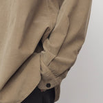 Side closeup view of beige corduroy sislia shirt on model wearing grey pants, against a white background.