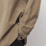 Side closeup view of beige corduroy sislia shirt on model wearing grey pants, against a white background.